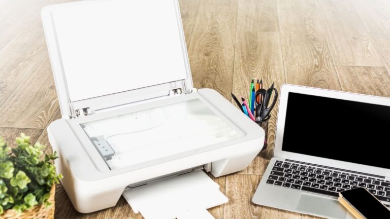 impressora branca ao lado de um notebook