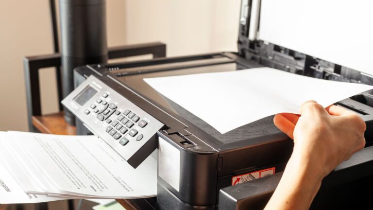 mão colocando papel na impressora a laser